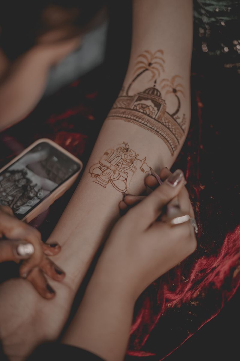 Close-up of traditional bridal mehndi design being applied by an artist on a woman's arm in India.