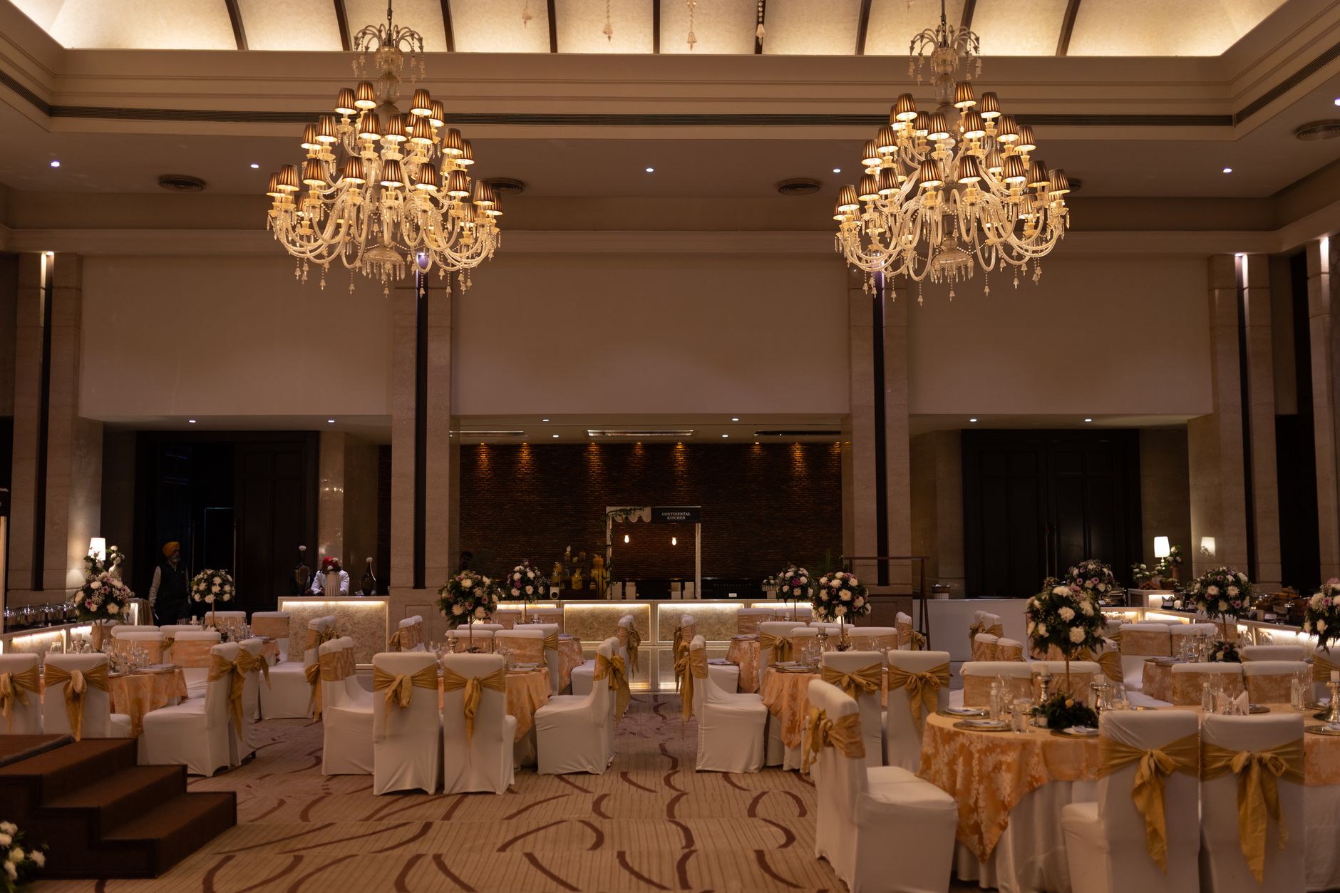 Luxurious ballroom decorated with grand chandeliers and floral arrangements for an elegant event.